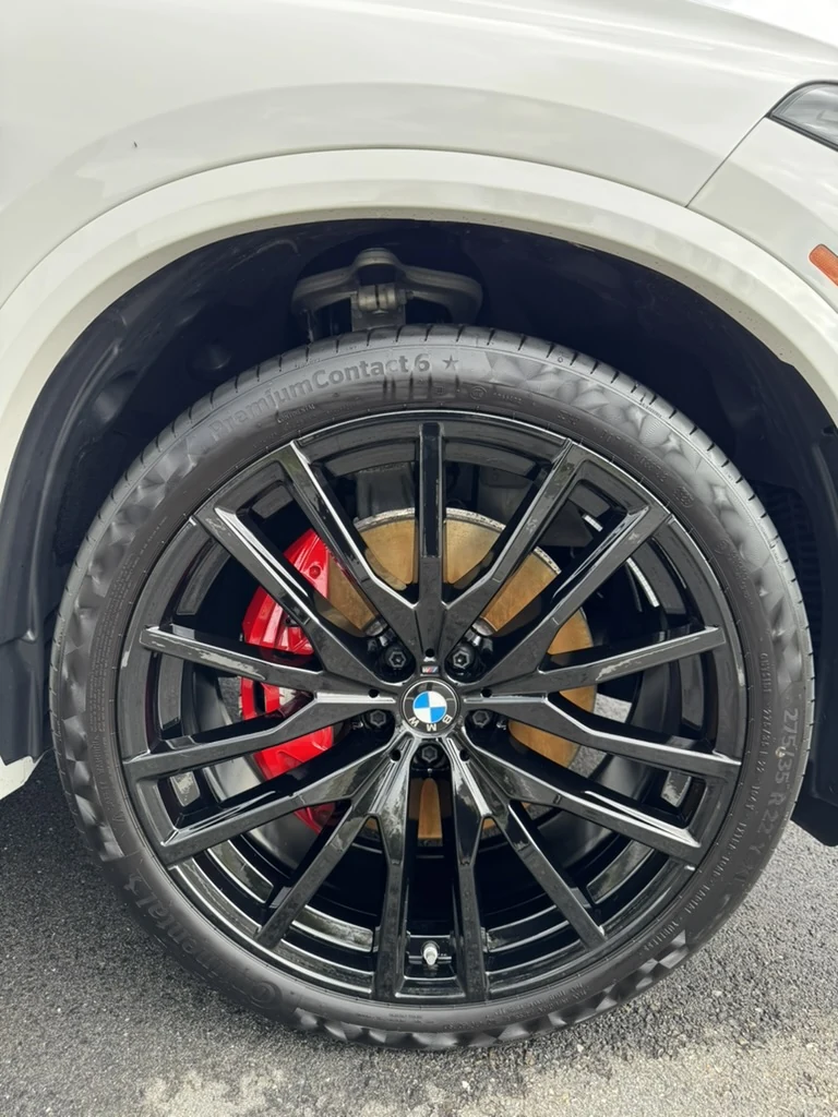 Clean black BMW wheel and tire, with a red brake caliper behind the spokes