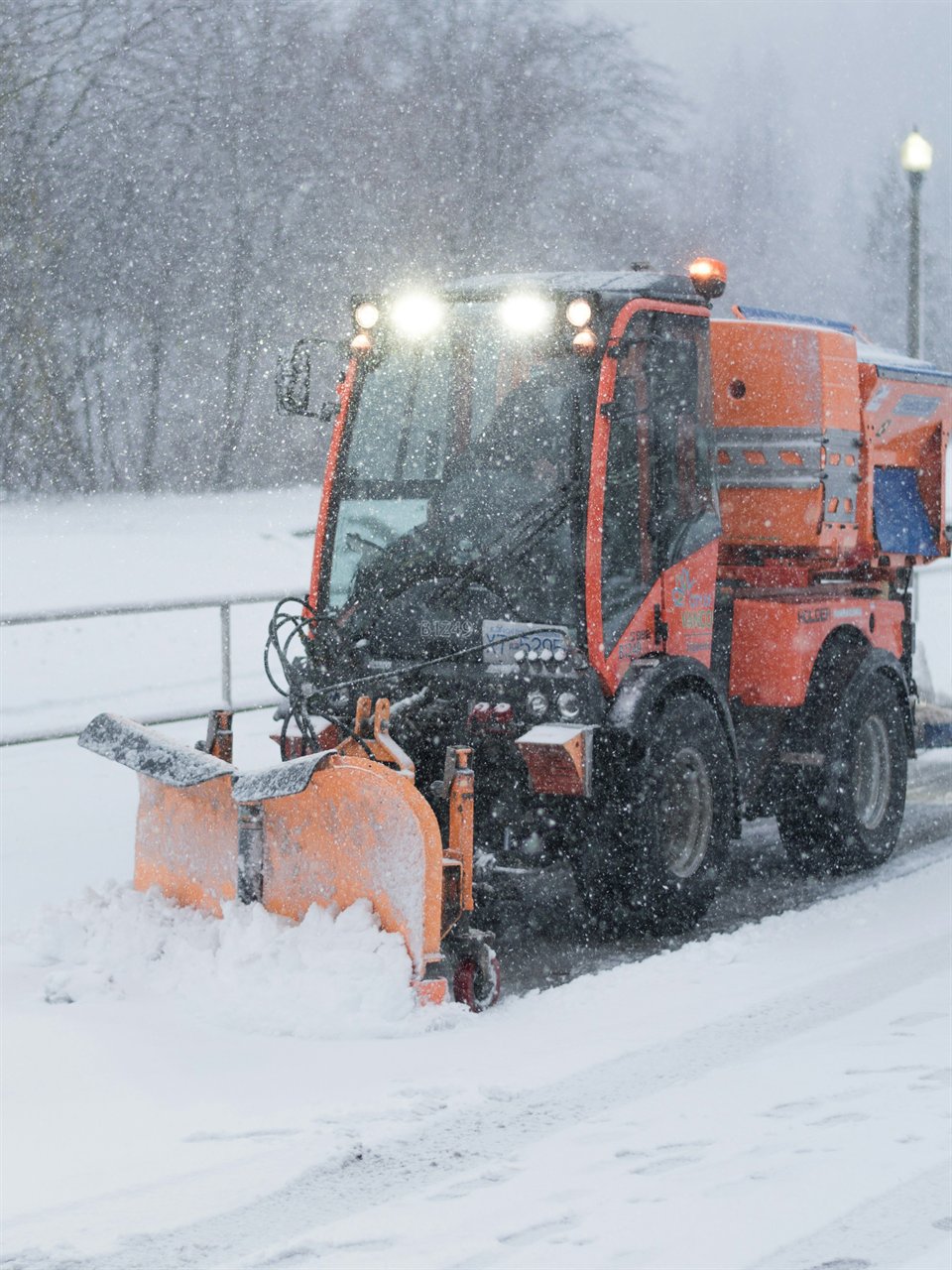 An orange plow clearing a snowy road